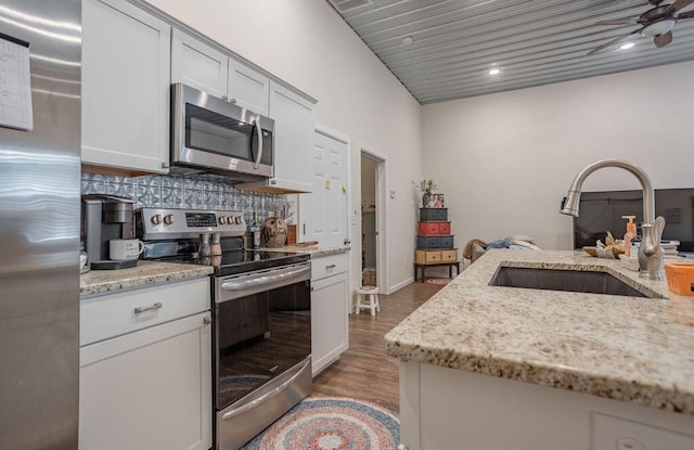 kitchen featuring light hardwood / wood-style floors, ceiling fan, sink, light stone countertops, and appliances with stainless steel finishes