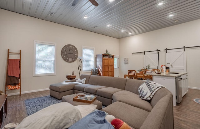 living room featuring ceiling fan, wood ceiling, sink, dark wood-type flooring, and a barn door