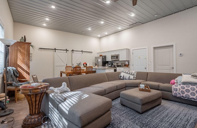 living room with a barn door, hardwood / wood-style flooring, and a towering ceiling