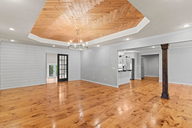 interior space with a notable chandelier, a raised ceiling, crown molding, and light hardwood / wood-style floors