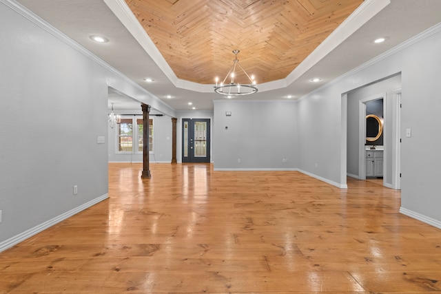 interior space with a raised ceiling, light hardwood / wood-style flooring, a chandelier, and ornamental molding