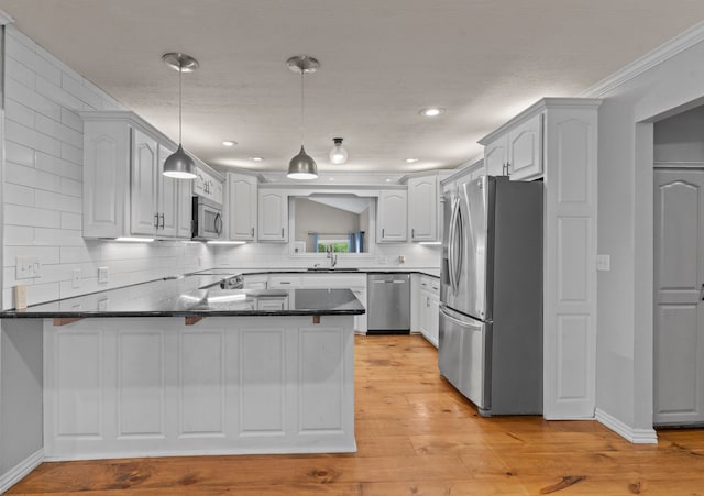 kitchen featuring hanging light fixtures, ornamental molding, kitchen peninsula, light hardwood / wood-style flooring, and appliances with stainless steel finishes