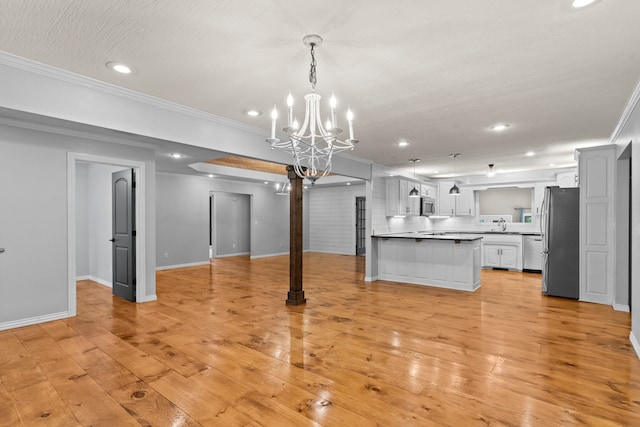 kitchen with decorative light fixtures, ornamental molding, appliances with stainless steel finishes, and light hardwood / wood-style floors