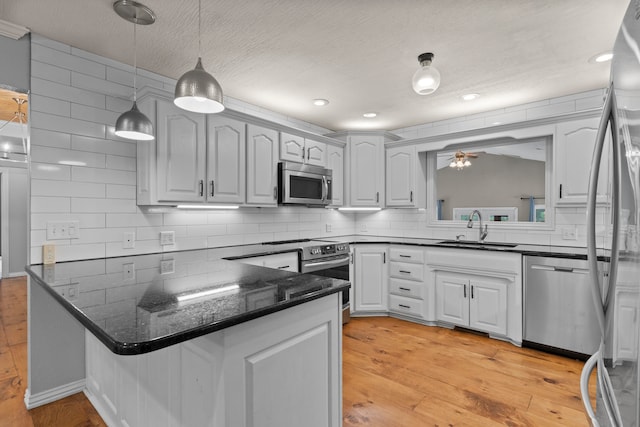 kitchen with appliances with stainless steel finishes, light wood-type flooring, white cabinetry, and sink