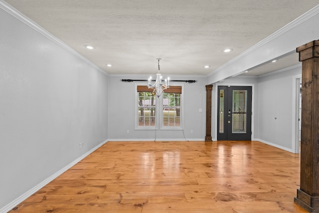 unfurnished dining area featuring light hardwood / wood-style floors, a textured ceiling, a chandelier, crown molding, and a barn door