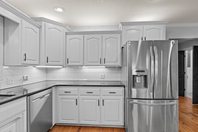 kitchen featuring white cabinets, stainless steel appliances, backsplash, and light hardwood / wood-style floors