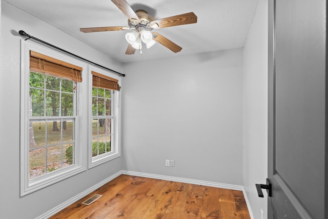 empty room featuring plenty of natural light, wood-type flooring, and ceiling fan