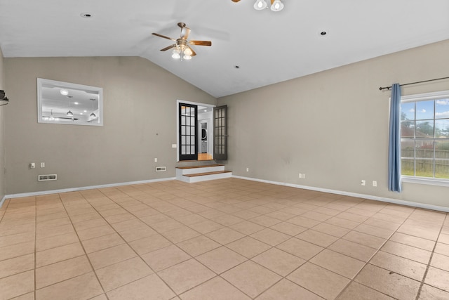 empty room with lofted ceiling, ceiling fan, and light tile patterned floors