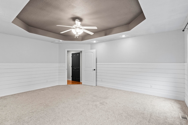 carpeted empty room with a tray ceiling, a textured ceiling, and ceiling fan