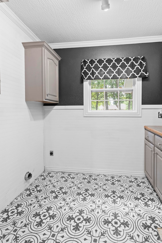 clothes washing area featuring ornamental molding and a textured ceiling