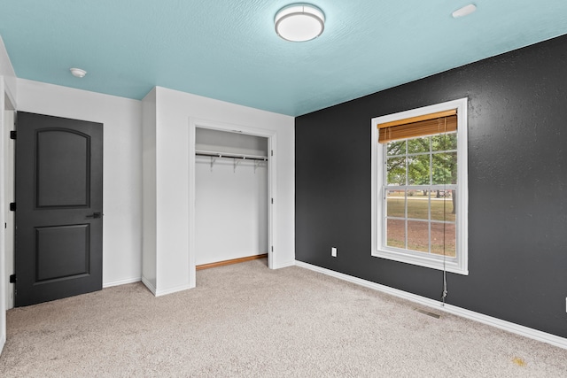 unfurnished bedroom with light colored carpet and a closet