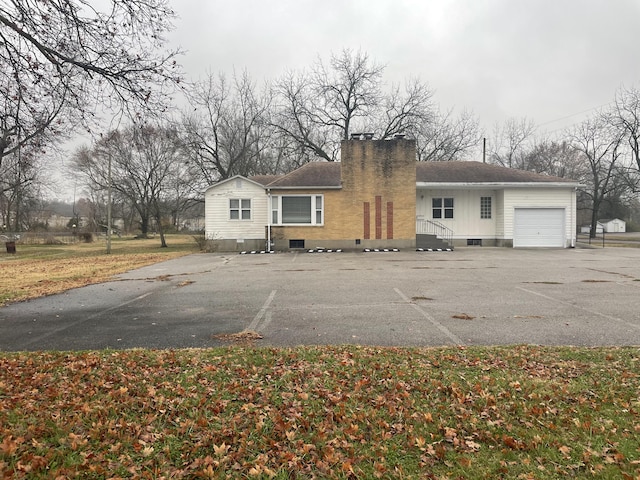 view of front of property with an attached garage, a shingled roof, and a chimney