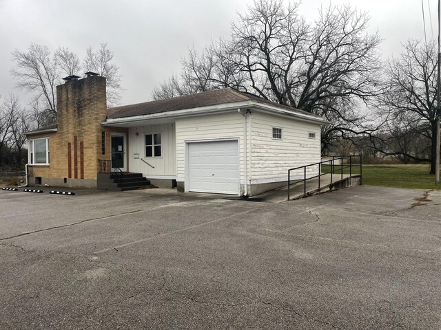 view of front of property featuring a chimney, an attached garage, and driveway