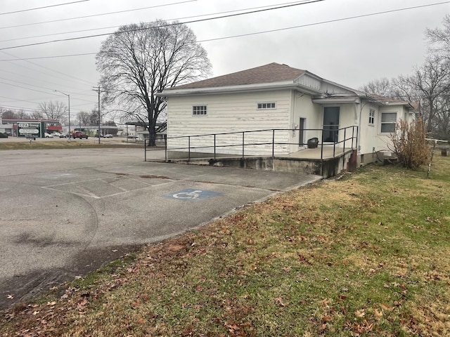 view of side of property with roof with shingles and a yard