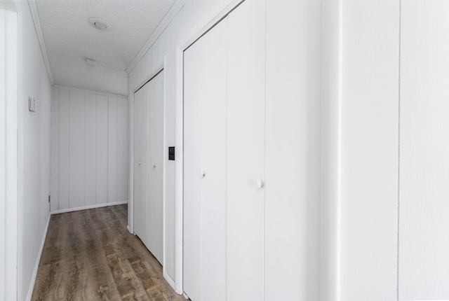 hallway featuring dark wood-type flooring, crown molding, and a textured ceiling