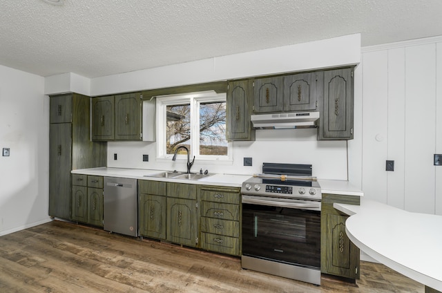 kitchen with green cabinetry, stainless steel appliances, dark wood-type flooring, sink, and a textured ceiling