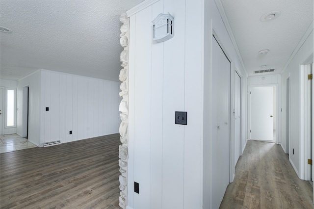 hallway featuring a textured ceiling, dark hardwood / wood-style floors, and wood walls