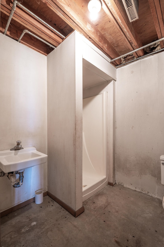 bathroom featuring toilet, a shower, and concrete flooring