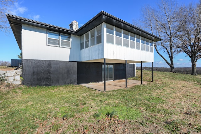 back of property featuring a sunroom, a lawn, and a patio area