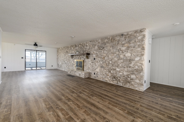 unfurnished living room featuring ceiling fan, a textured ceiling, a fireplace, and dark wood-type flooring