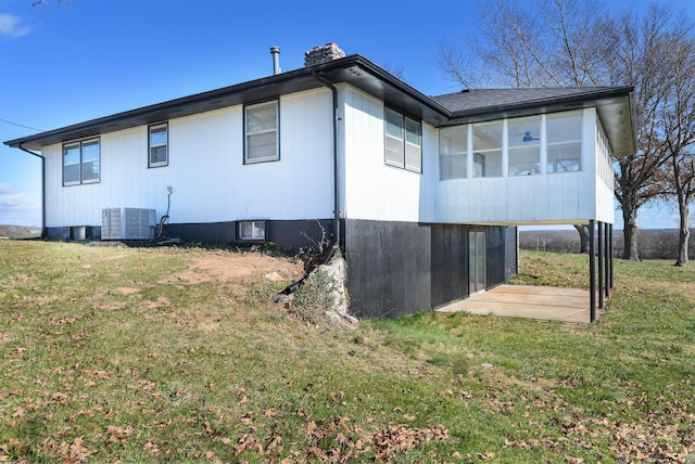 view of property exterior with a sunroom, central air condition unit, and a lawn