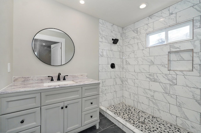 bathroom with tile patterned floors, a tile shower, and vanity