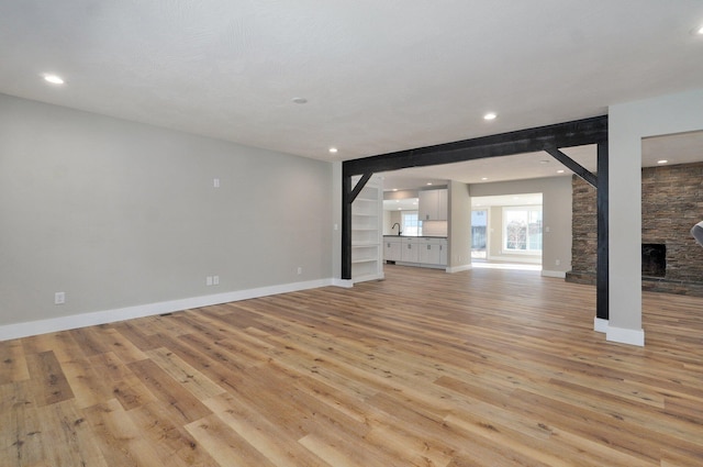 unfurnished living room featuring a fireplace, sink, light wood-type flooring, and a textured ceiling