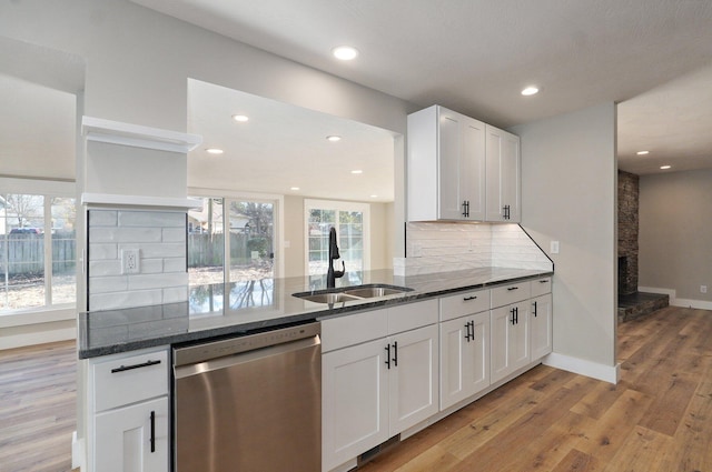 kitchen featuring light wood-type flooring, tasteful backsplash, sink, white cabinets, and stainless steel dishwasher