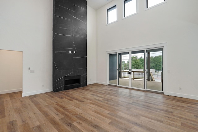 unfurnished living room featuring a high ceiling, light wood-type flooring, and a fireplace