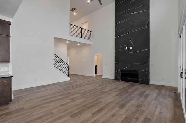 unfurnished living room with a fireplace, hardwood / wood-style floors, and a high ceiling