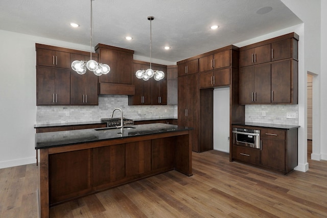 kitchen with pendant lighting, wood-type flooring, stainless steel oven, and dark brown cabinetry