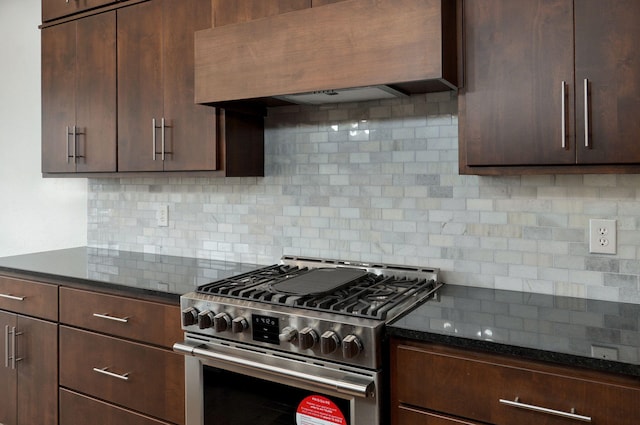 kitchen featuring dark brown cabinetry, high end stainless steel range, backsplash, custom range hood, and dark stone counters