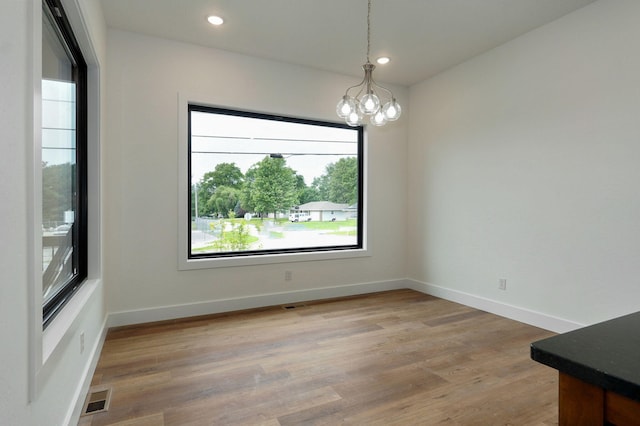 unfurnished dining area featuring hardwood / wood-style floors and a notable chandelier