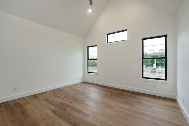 spare room with high vaulted ceiling and light hardwood / wood-style flooring