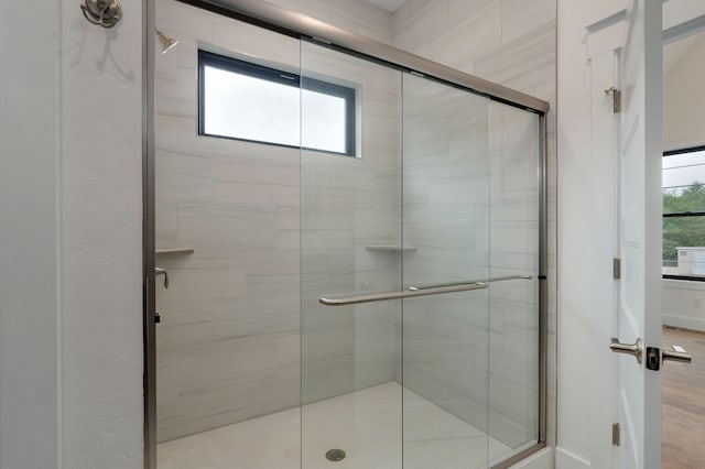 bathroom with an enclosed shower, wood-type flooring, and a healthy amount of sunlight