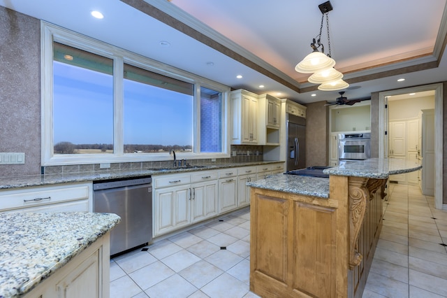 kitchen featuring hanging light fixtures, sink, a kitchen island, stainless steel appliances, and light stone countertops