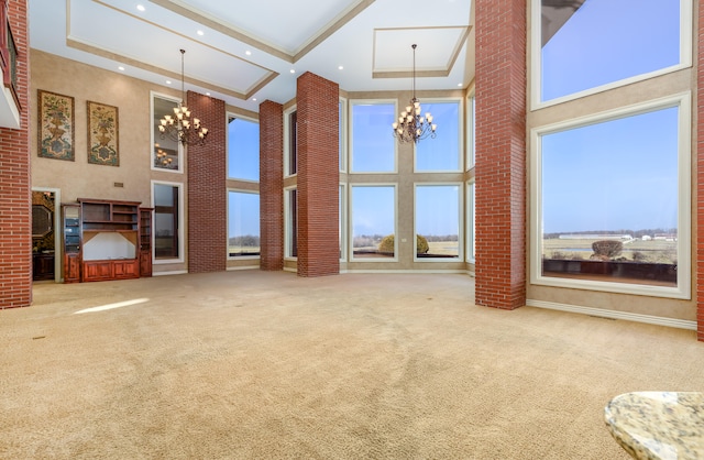 unfurnished living room featuring a towering ceiling, carpet, and a notable chandelier