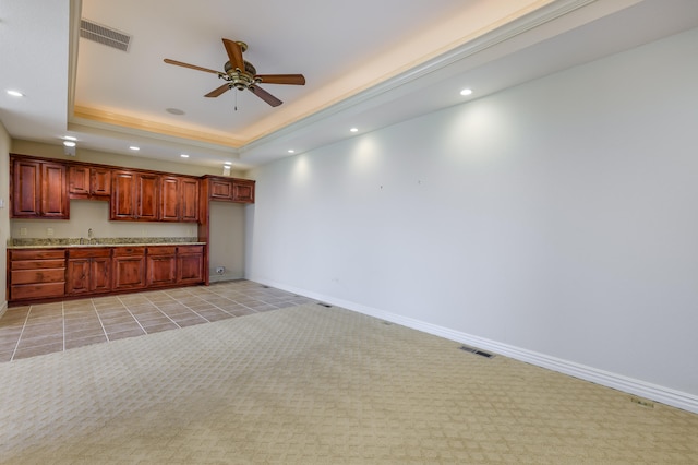 kitchen with a raised ceiling, light colored carpet, sink, and ceiling fan