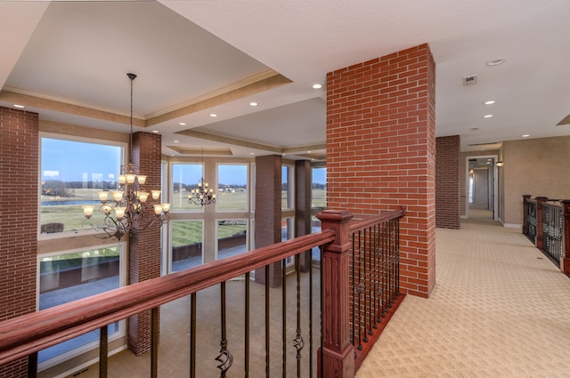 hall featuring light carpet, a notable chandelier, a tray ceiling, and crown molding