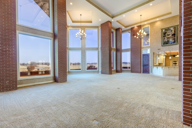 unfurnished living room featuring a towering ceiling, plenty of natural light, and carpet floors