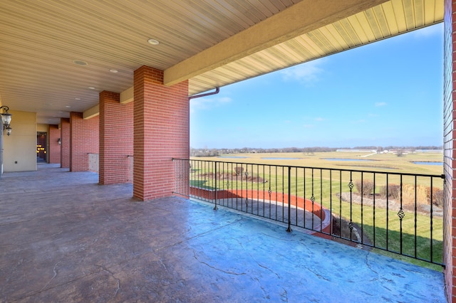 view of patio with a balcony and a rural view