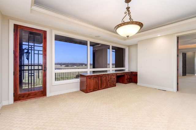 interior space featuring a tray ceiling, light carpet, crown molding, and built in desk