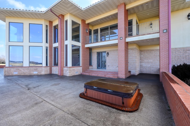 exterior space featuring a covered hot tub and a balcony