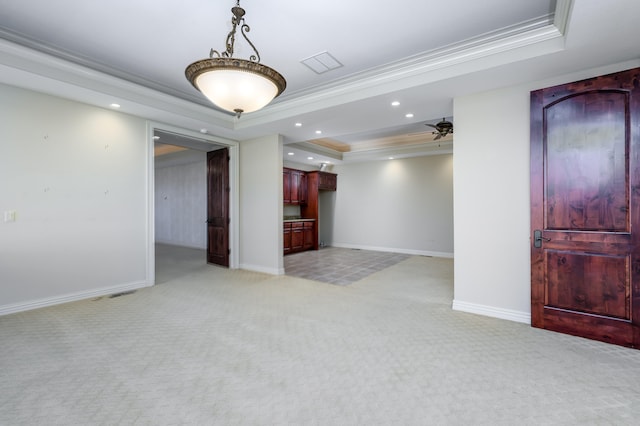 spare room featuring ceiling fan, crown molding, a tray ceiling, and light colored carpet