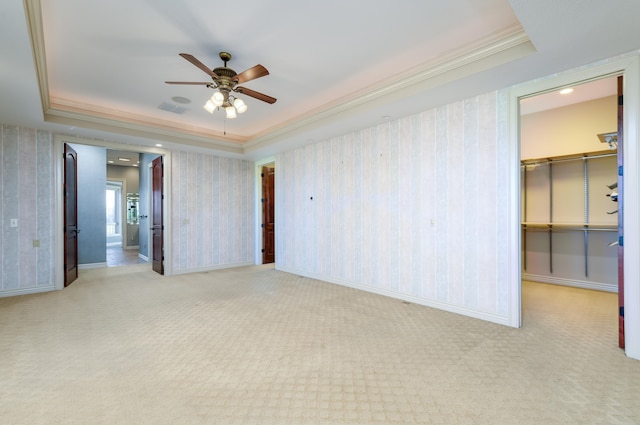 carpeted empty room with a raised ceiling, crown molding, and ceiling fan