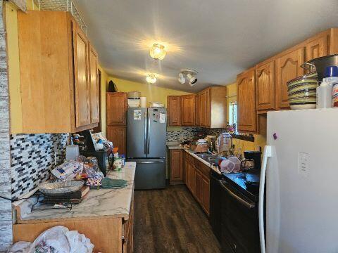 kitchen with stainless steel fridge, white fridge, backsplash, dark wood-type flooring, and vaulted ceiling