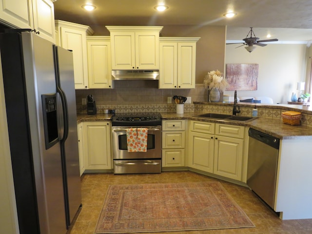 kitchen with sink, backsplash, dark tile patterned flooring, ceiling fan, and stainless steel appliances