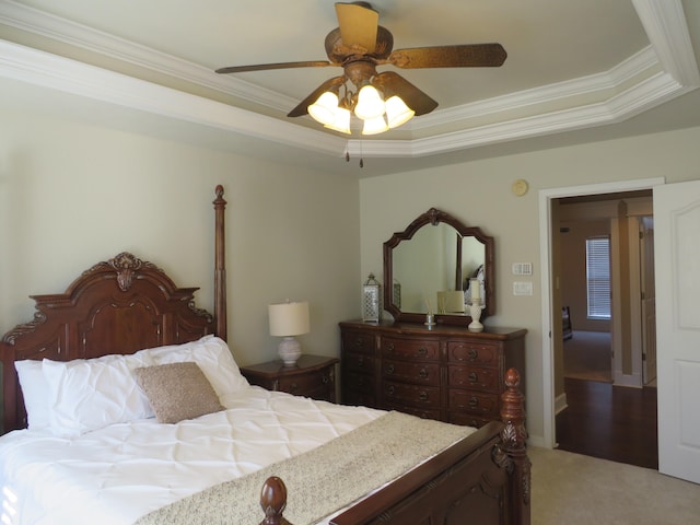 carpeted bedroom with crown molding, ceiling fan, and a tray ceiling