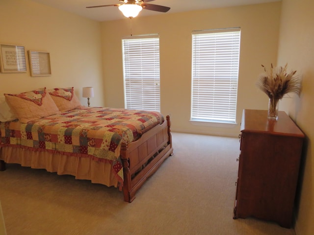 bedroom featuring ceiling fan, light colored carpet, and multiple windows