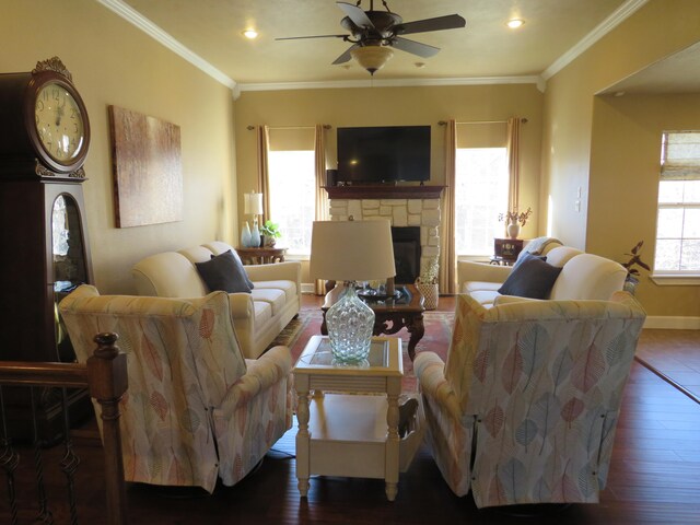 living room featuring ceiling fan, ornamental molding, dark hardwood / wood-style floors, and a stone fireplace